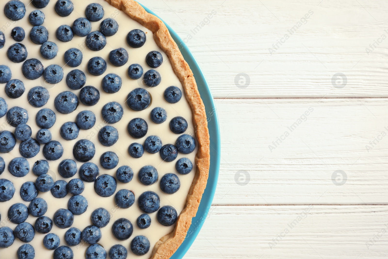 Photo of Tasty blueberry cake on wooden background, top view with space for text