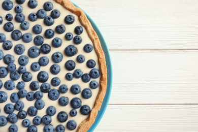 Photo of Tasty blueberry cake on wooden background, top view with space for text