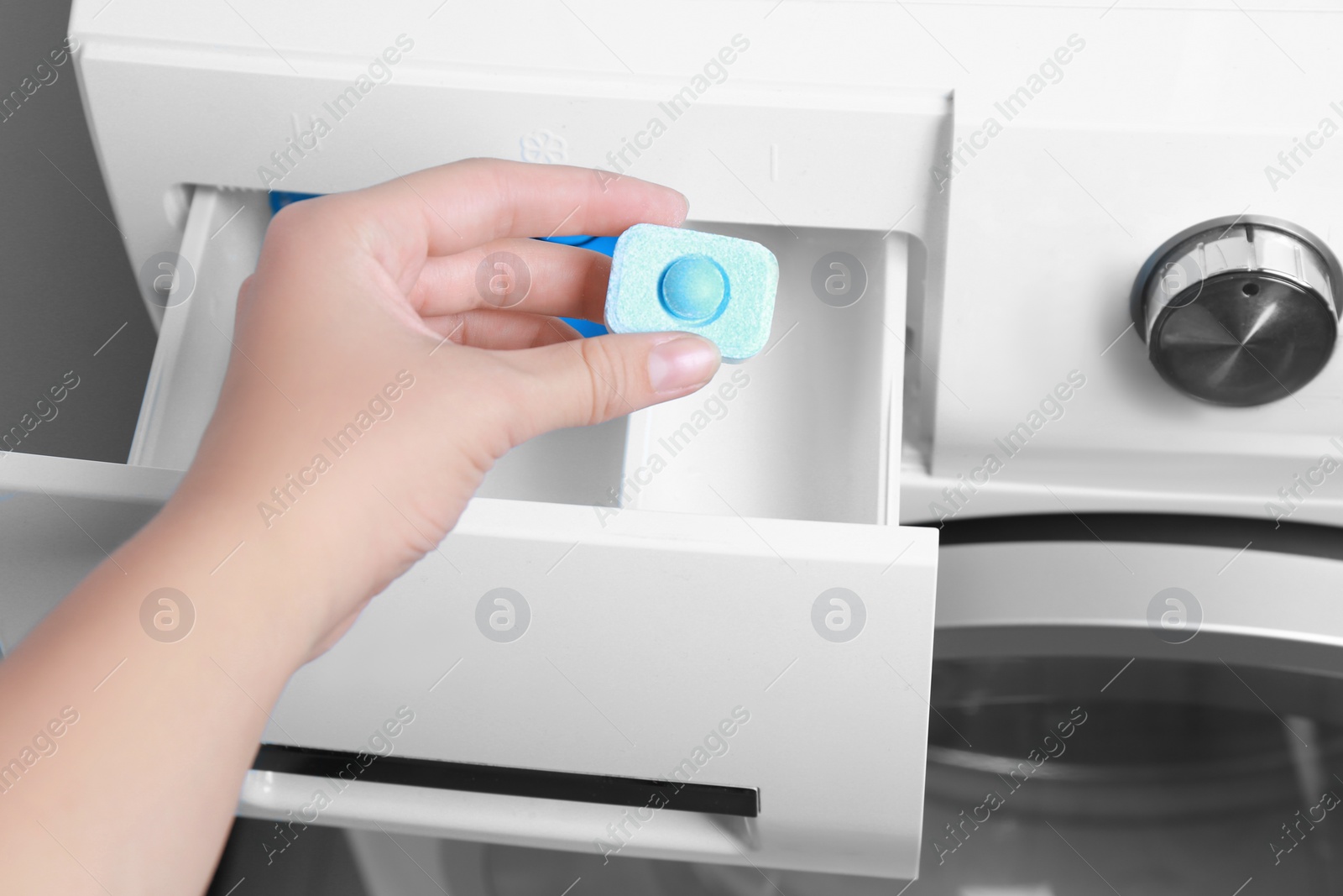 Photo of Woman putting water softener tablet into washing machine, closeup