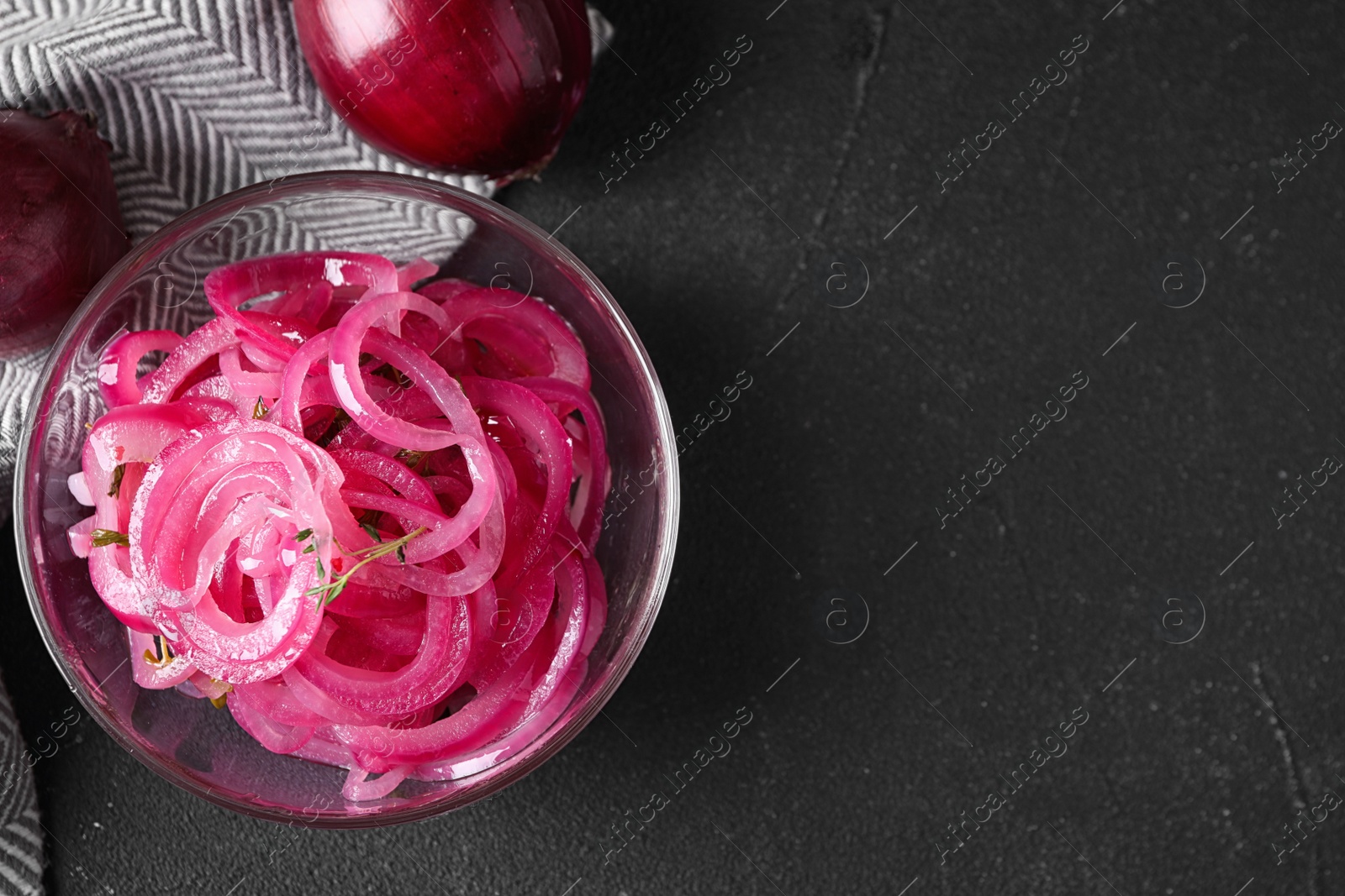 Photo of Bowl with tasty pickled onions on black table, top view. Space for text