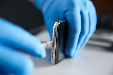 Photo of Technician repairing mobile phone at table, closeup