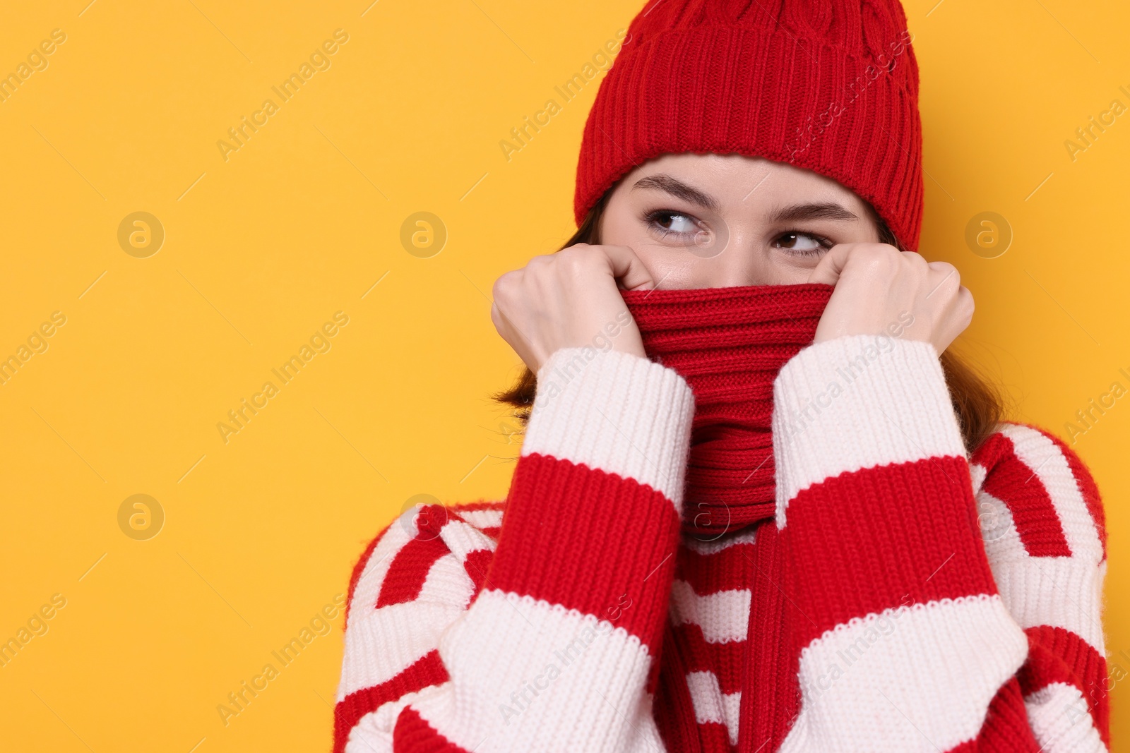 Photo of Beautiful woman in warm scarf on yellow background, space for text