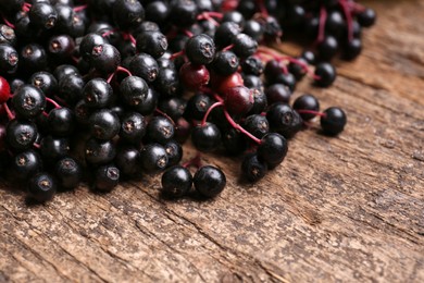 Photo of Pile of tasty elderberries (Sambucus) on wooden table, closeup. Space for text