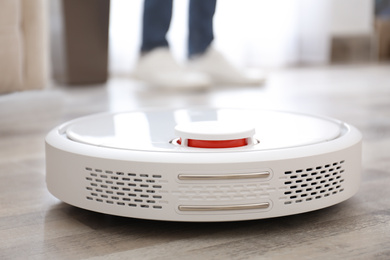 Photo of Man using robotic vacuum cleaner at home