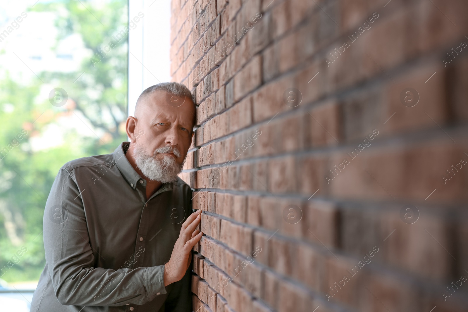 Photo of Senior man in state of depression near brick wall