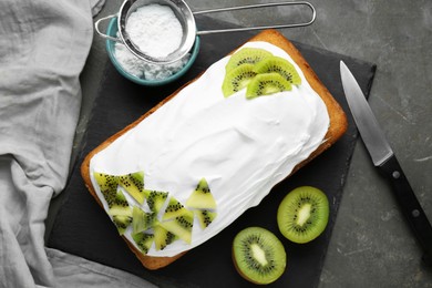 Delicious homemade yogurt cake with kiwi and cream on gray table, flat lay