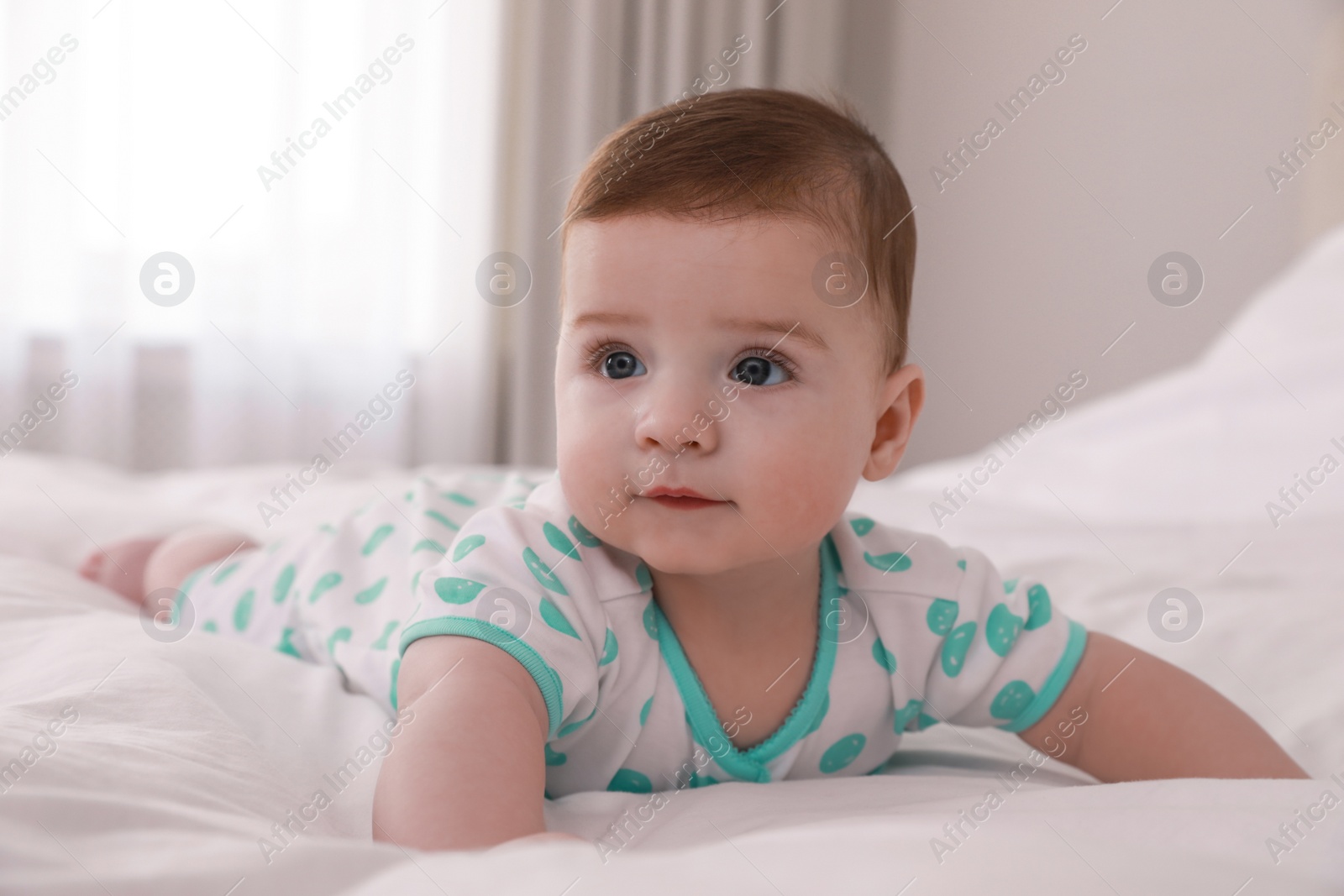 Photo of Cute little baby lying on bed with soft blanket indoors