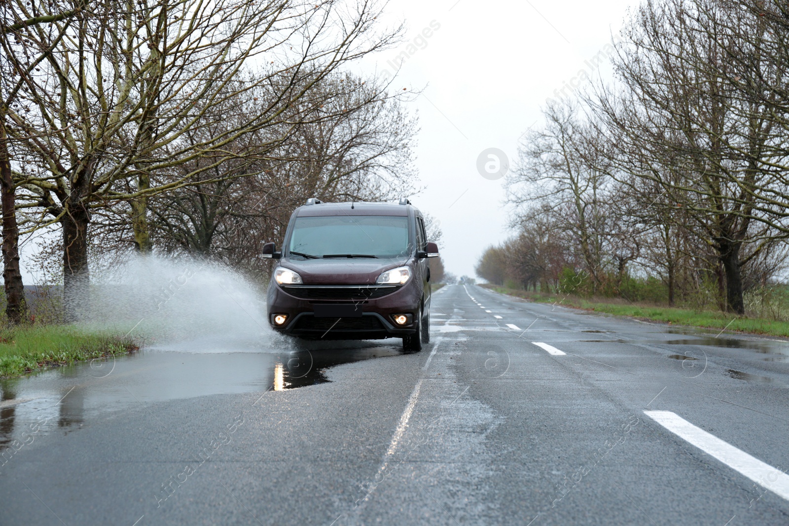 Photo of Wet suburban road with car on rainy day