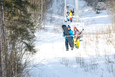 Photo of Couple using chairlift at mountain ski resort. Winter vacation