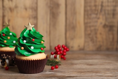 Christmas tree shaped cupcakes on wooden table. Space for text
