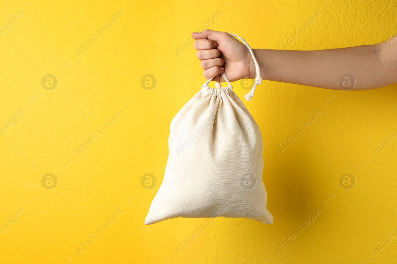 Photo of Woman holding full cotton eco bag on yellow background, closeup
