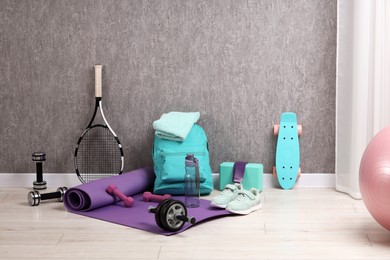 Photo of Many different sports equipment near grey wall indoors