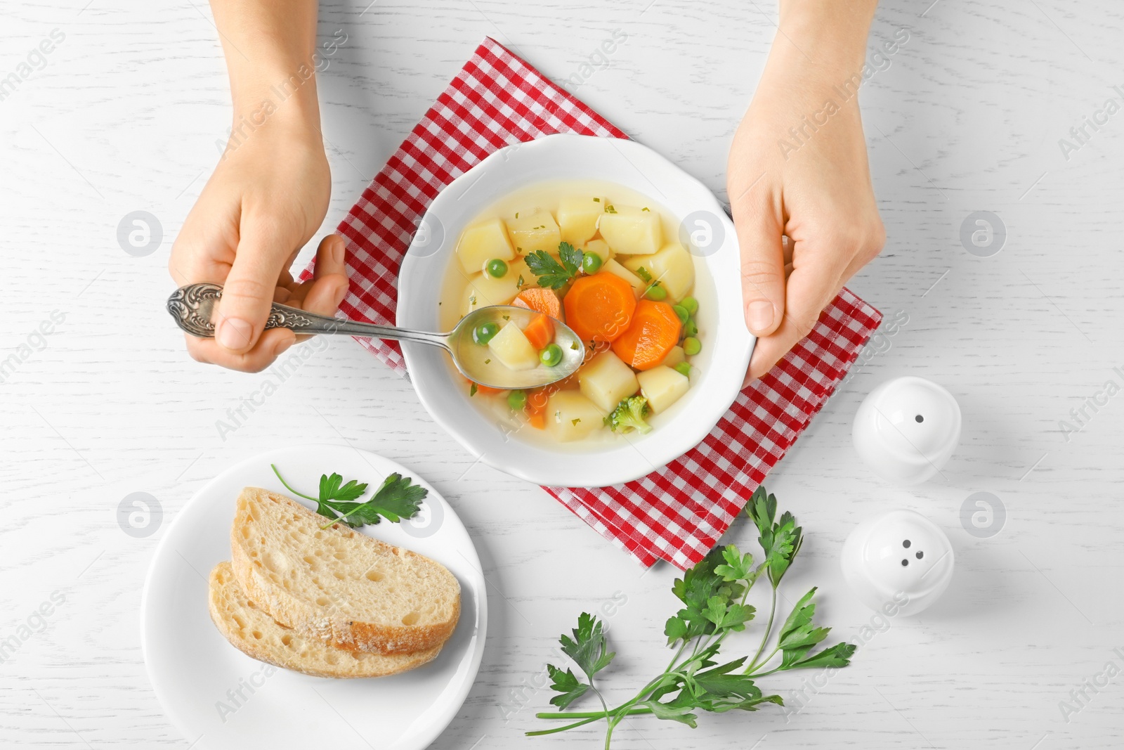 Photo of Woman eating fresh homemade vegetable soup at white wooden table, top view