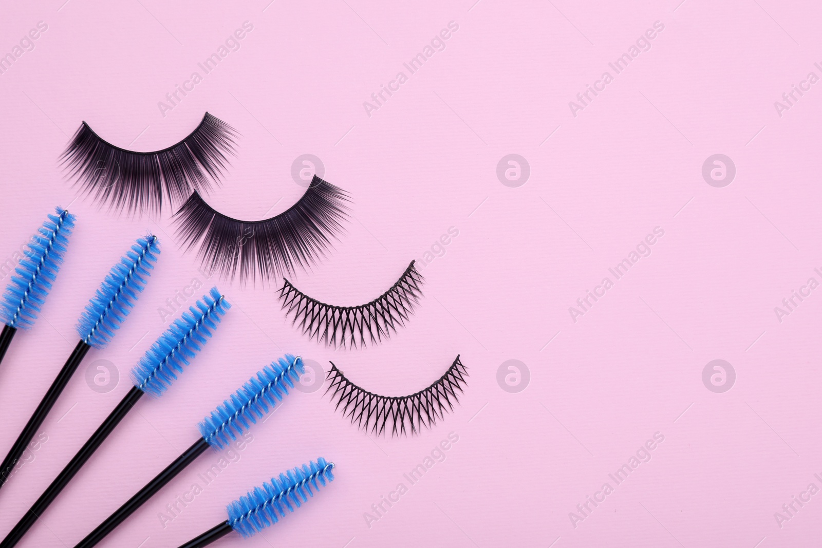 Photo of Fake eyelashes and brushes on pink background, flat lay. Space for text