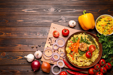 Photo of Flat lay composition with tasty rice pilaf on wooden table. Space for text