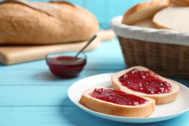 Photo of Slices of tasty fresh bread with jam on light blue wooden table