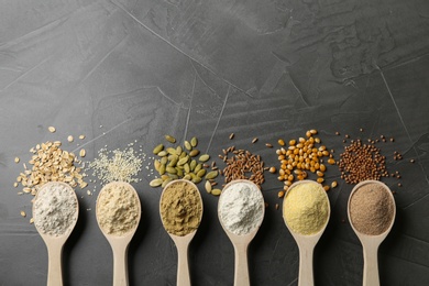 Photo of Spoons with different types of flour and ingredients on grey background, top view. Space for text