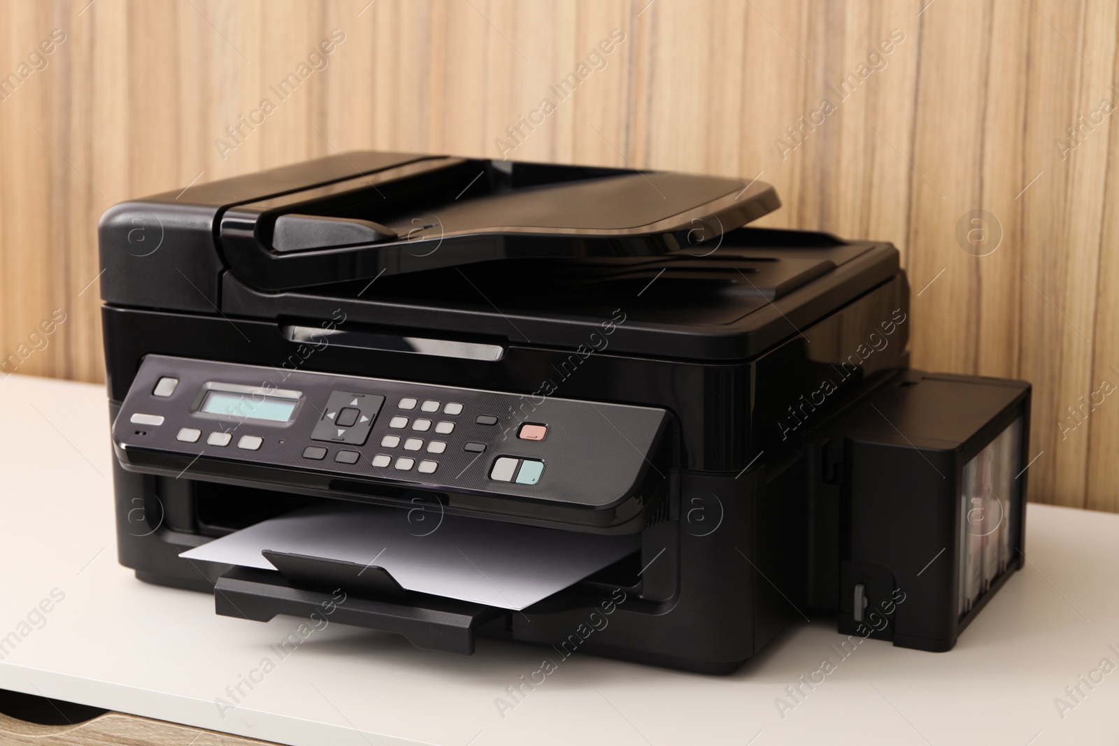 Photo of New modern printer on white table against wooden background