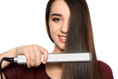 Happy woman using hair iron on white background