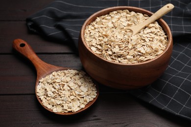 Photo of Bowl with scoop and spoon of oatmeal on wooden table