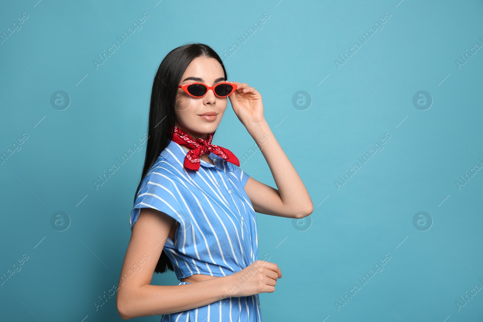 Photo of Fashionable young woman in stylish outfit with bandana on light blue background, space for text