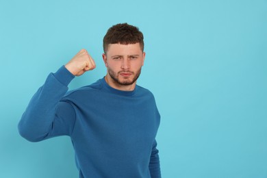 Photo of Aggressive young man on light blue background, Space for text