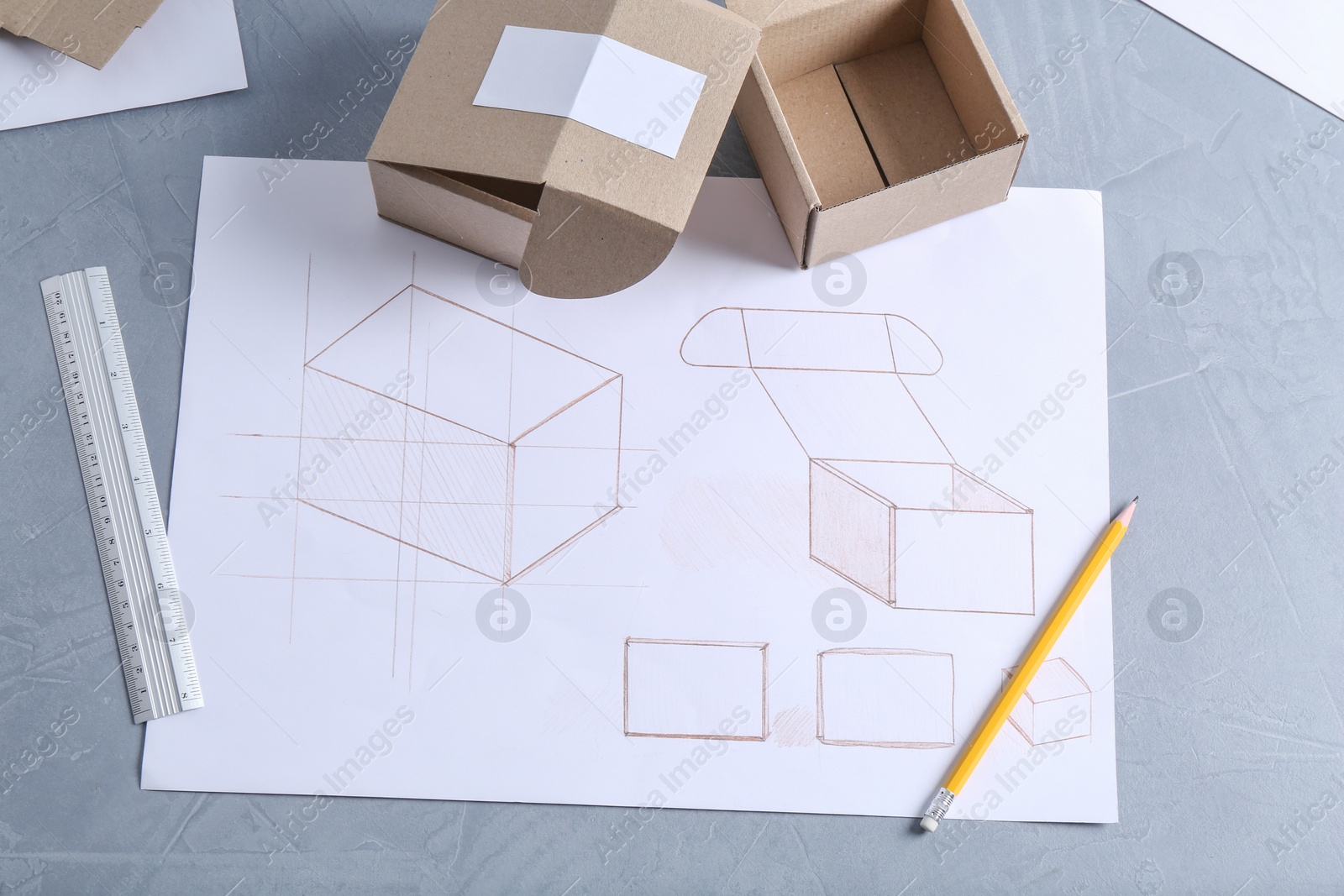 Photo of Creating packaging design. Drawings, boxes and stationery on blue textured table, flat lay