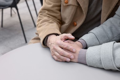Affectionate senior couple sitting at table in outdoor cafe, closeup