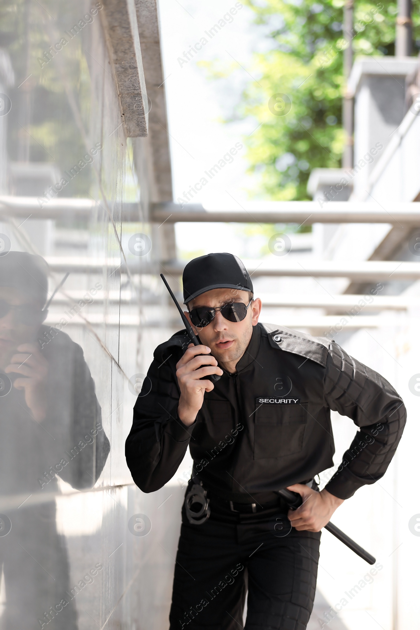 Photo of Male security guard using portable radio transmitter outdoors