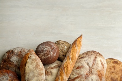Photo of Different kinds of fresh bread on white wooden table, flat lay. Space for text