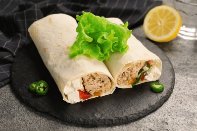 Delicious tortilla wraps with tuna on grey table