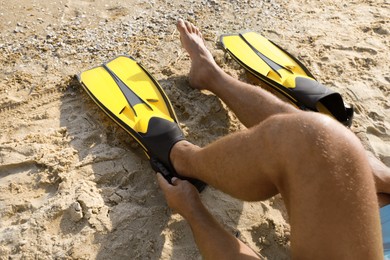 Man wearing flippers on beach, closeup view