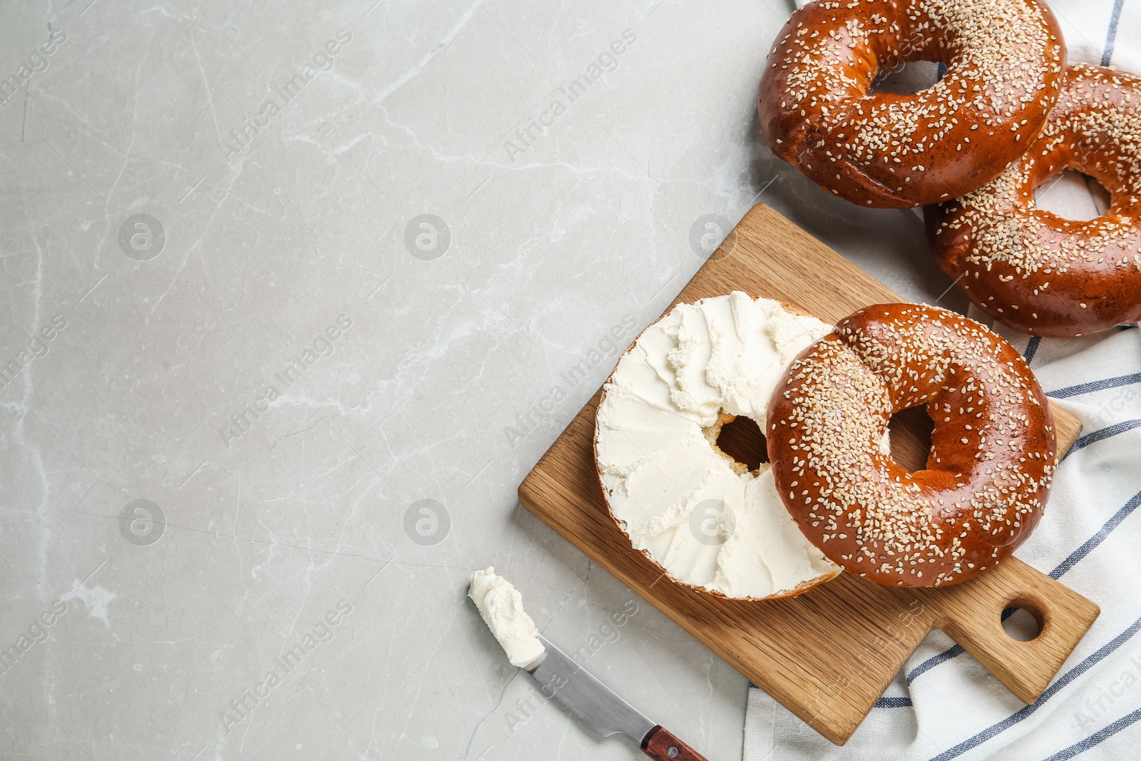 Photo of Delicious bagel with cream cheese on light table, flat lay. Space for text