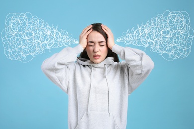 Stressed and upset young woman on light blue background