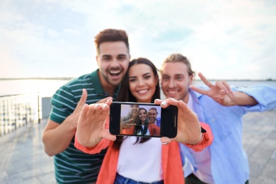 Happy young people taking selfie outdoors on sunny day