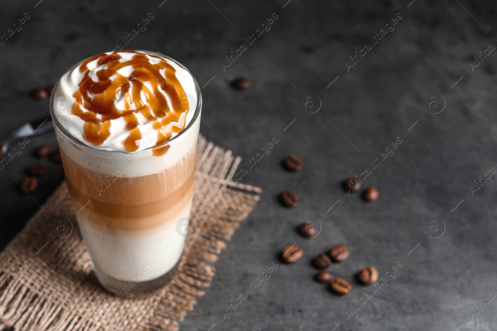 Photo of Glass with delicious caramel frappe on grey background