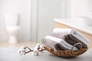 Photo of Basket with fresh towels on table in bathroom