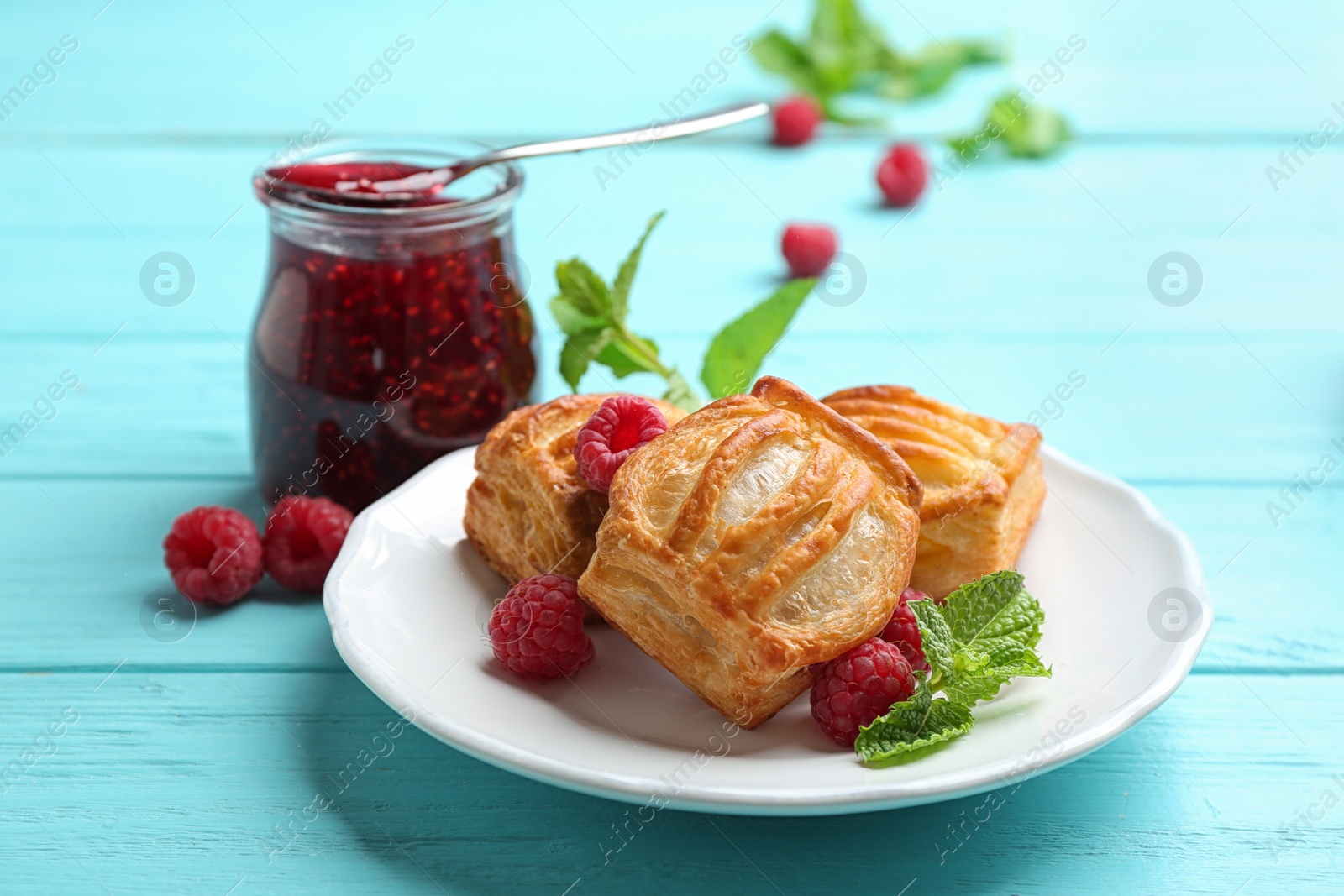 Photo of Fresh delicious puff pastry with sweet berries served on light blue wooden table