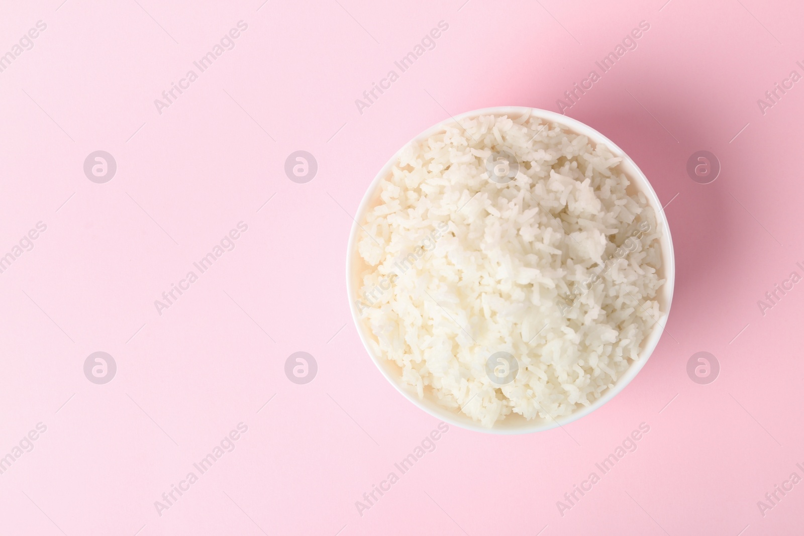 Photo of Bowl of boiled rice on color background, top view with space for text