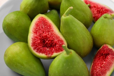 Photo of Cut and whole green figs on light blue plate, closeup
