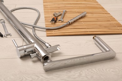 Photo of Professional plumbing tools and water tap on floor in bathroom