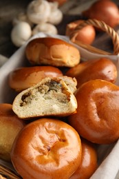 Photo of Wicker basket with delicious baked mushrooms and onion pirozhki