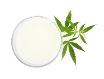 Glass of hemp milk and green leaves on white background, top view