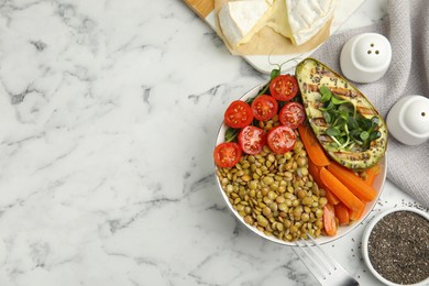 Delicious lentil bowl with avocado, tomatoes and carrots on white marble table, flat lay. Space for text