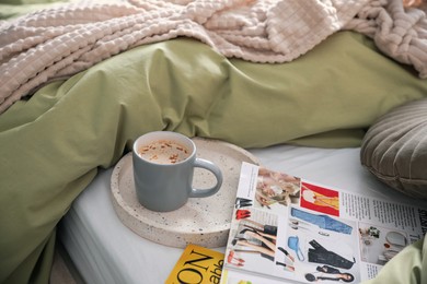 Photo of Aromatic coffee and magazines on bed with linens indoors