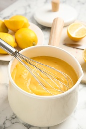 Photo of Delicious lemon curd and whisk on white marble table