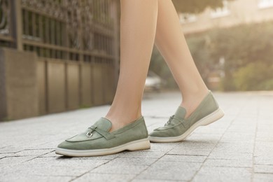 Woman in stylish loafers walking on city street, closeup