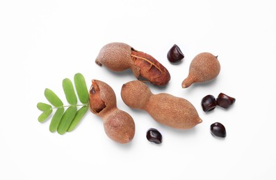 Photo of Ripe tamarinds and fresh leaves on white background, top view