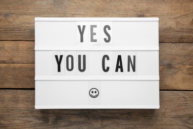 Lightbox with motivational quote Yes You Can on wooden background, top view