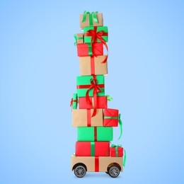 Many gifts on cardboard box with wheels against light blue background. Delivery service